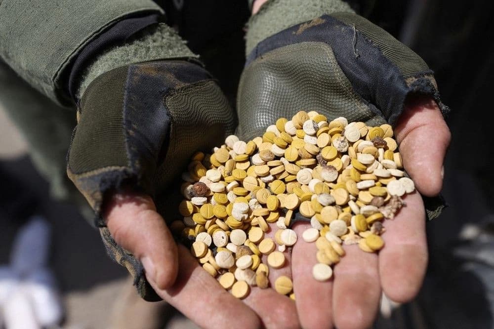 Fighter affiliated with Syria's "Hayat Tahrir al-Sham" (HTS) rebel-group display drugs previously seized at northern Aleppo province, on April 10, 2022. Photo: AFP