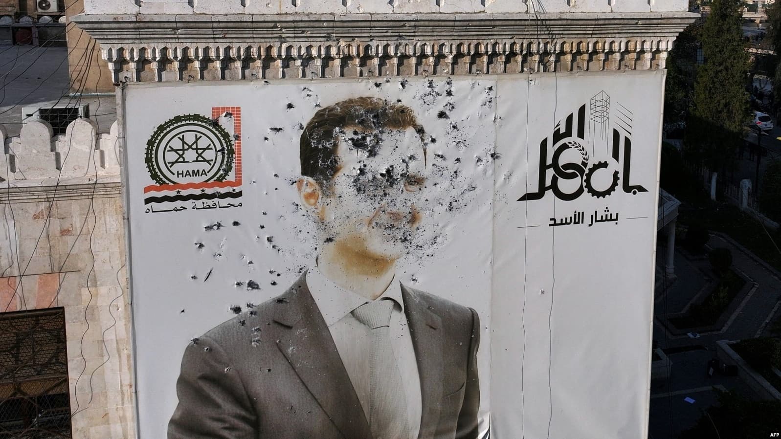 وێنەیەکی بەشار ئەسەد لەکاتی راپەڕینەکە لە پارێزگای حەما بەر گوللـە دراوە. وێنە: AFP