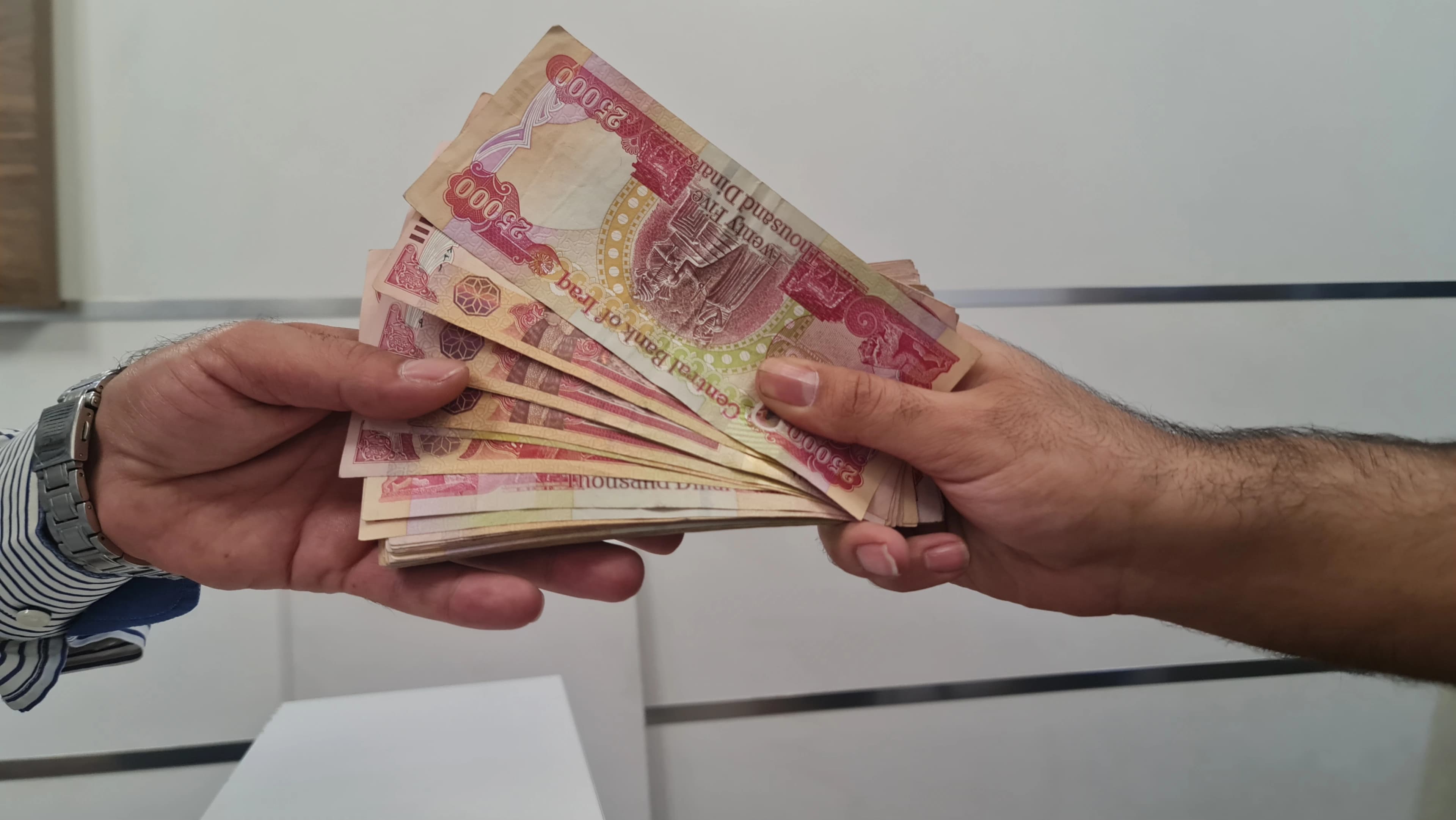 کەسێک پارە لە یەکێکی دیکە وەردەگرێت. وێنە؛ بڵندا تاهیر - رووداو