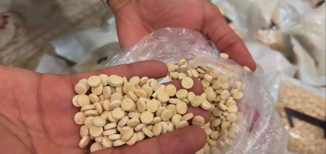 An anti-drug officer inspecting the Captagon pill they have seized. Photo: Screengrab from a video of the Iraqi anti-drug directorate