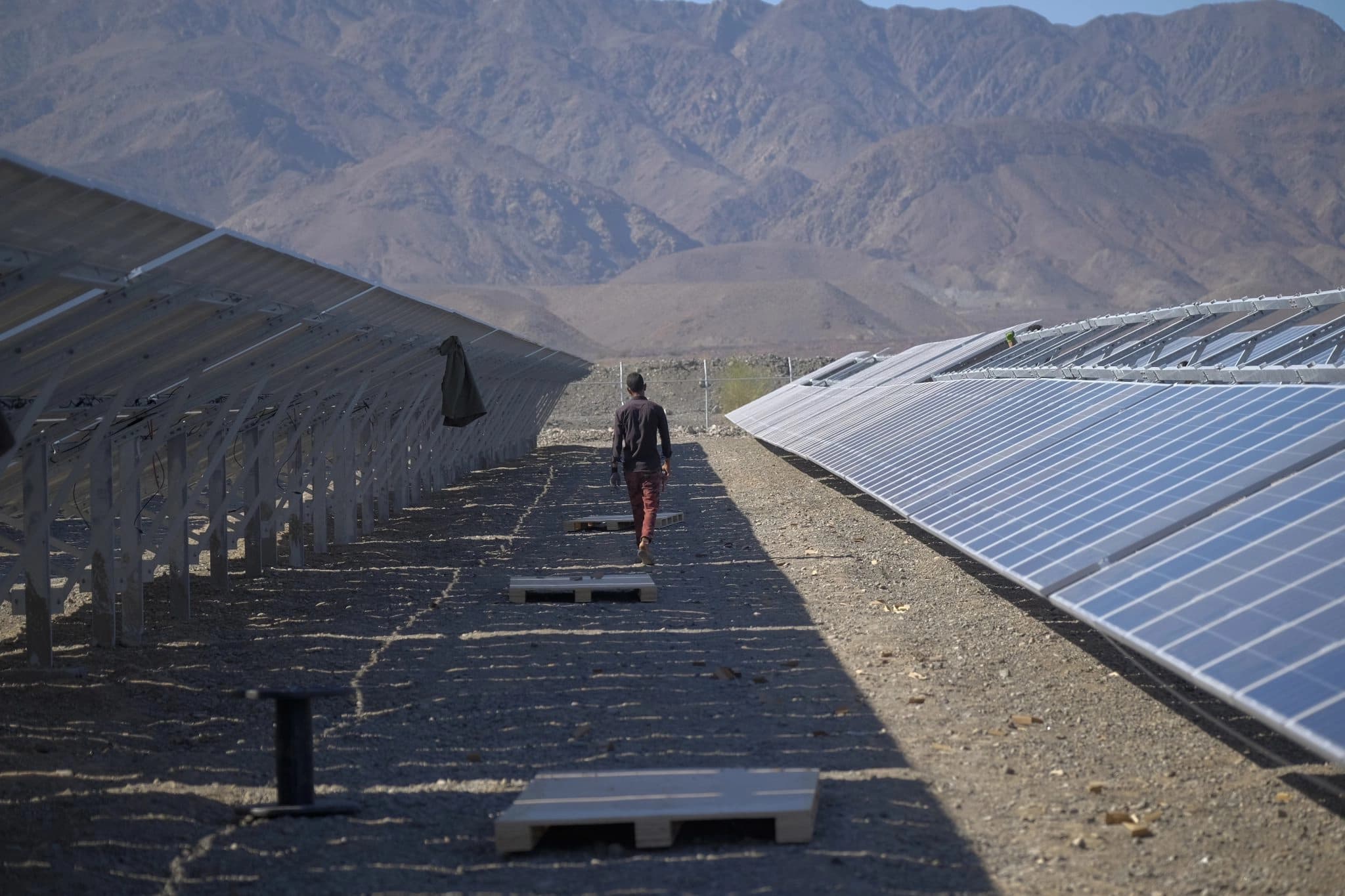 An Iranian worker walks past solar panels in the Qaleh Ganj area about 1372 km southeast of Tehran in Kerman province. Photo: AP