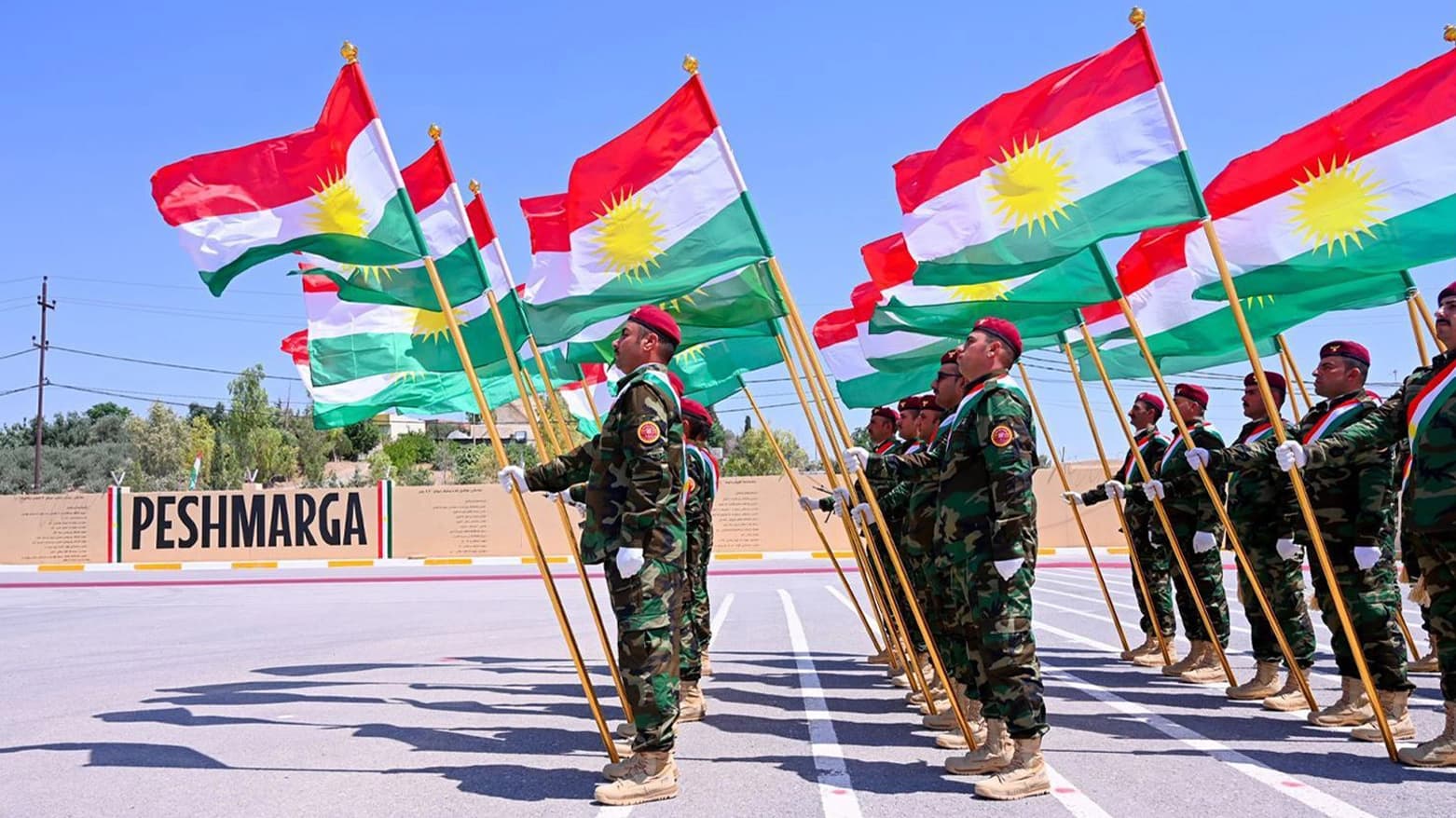 وێنەی ژمارەیەک پێشمەرگە بە ئاڵای کوردستانەوە نمایش دەکەن