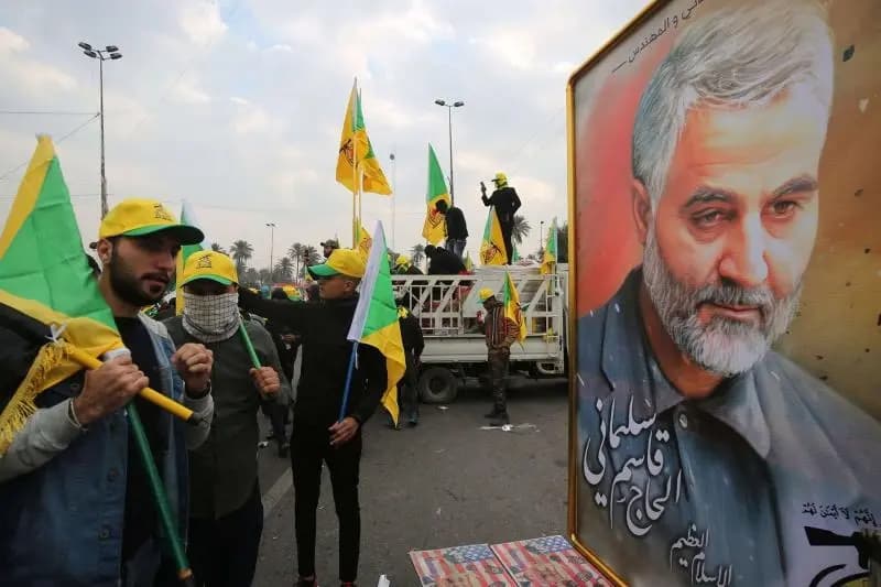 Öldürülen Kasım Süleymani'nin posterinin yanında duran Kataib Hizbullah destekçileri. / Fotoğraf: AFP