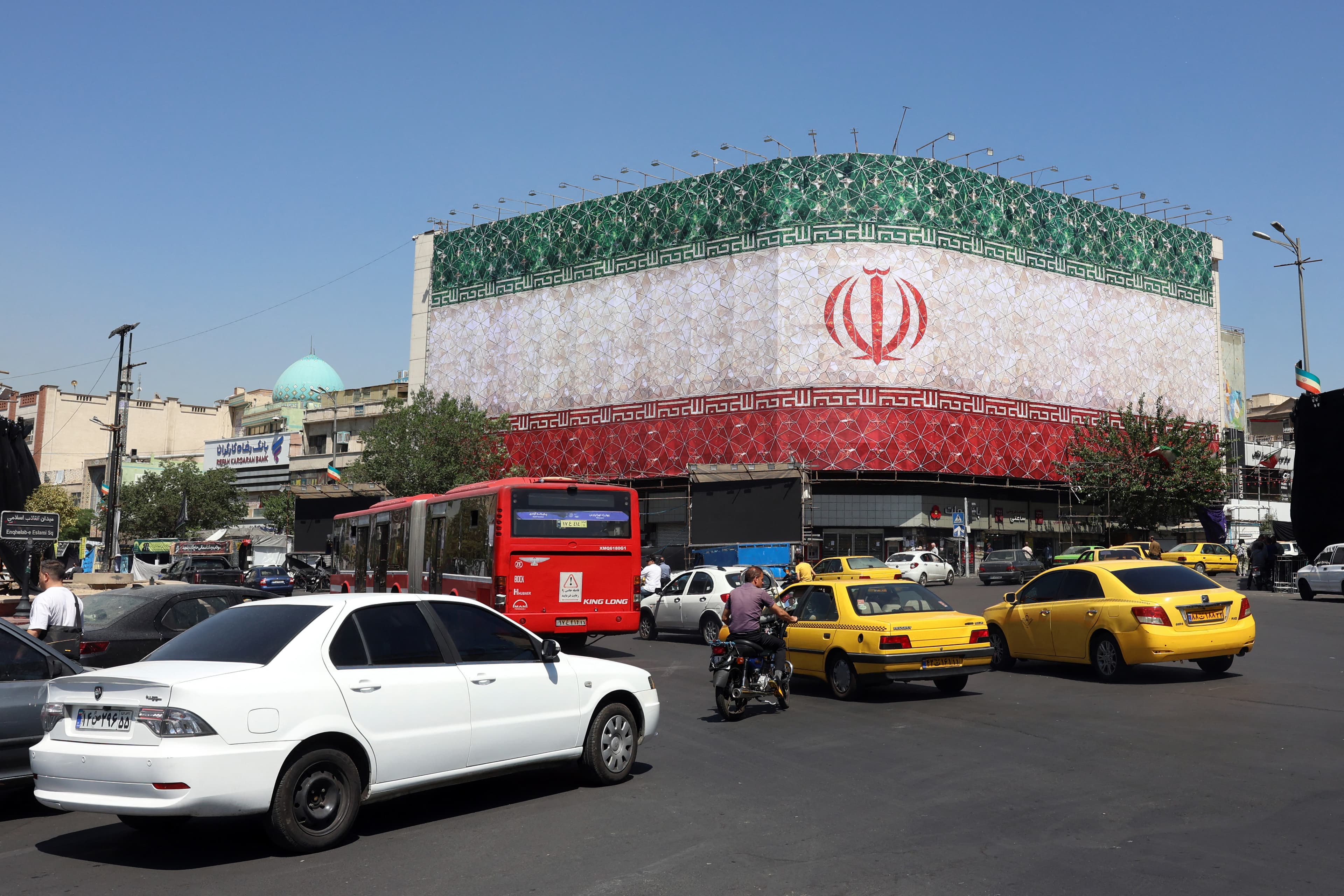 Traffic moves past the Iranian national flag displayed on a building at Enghelab square in Tehran on June 14, 2026. Photo: AFP