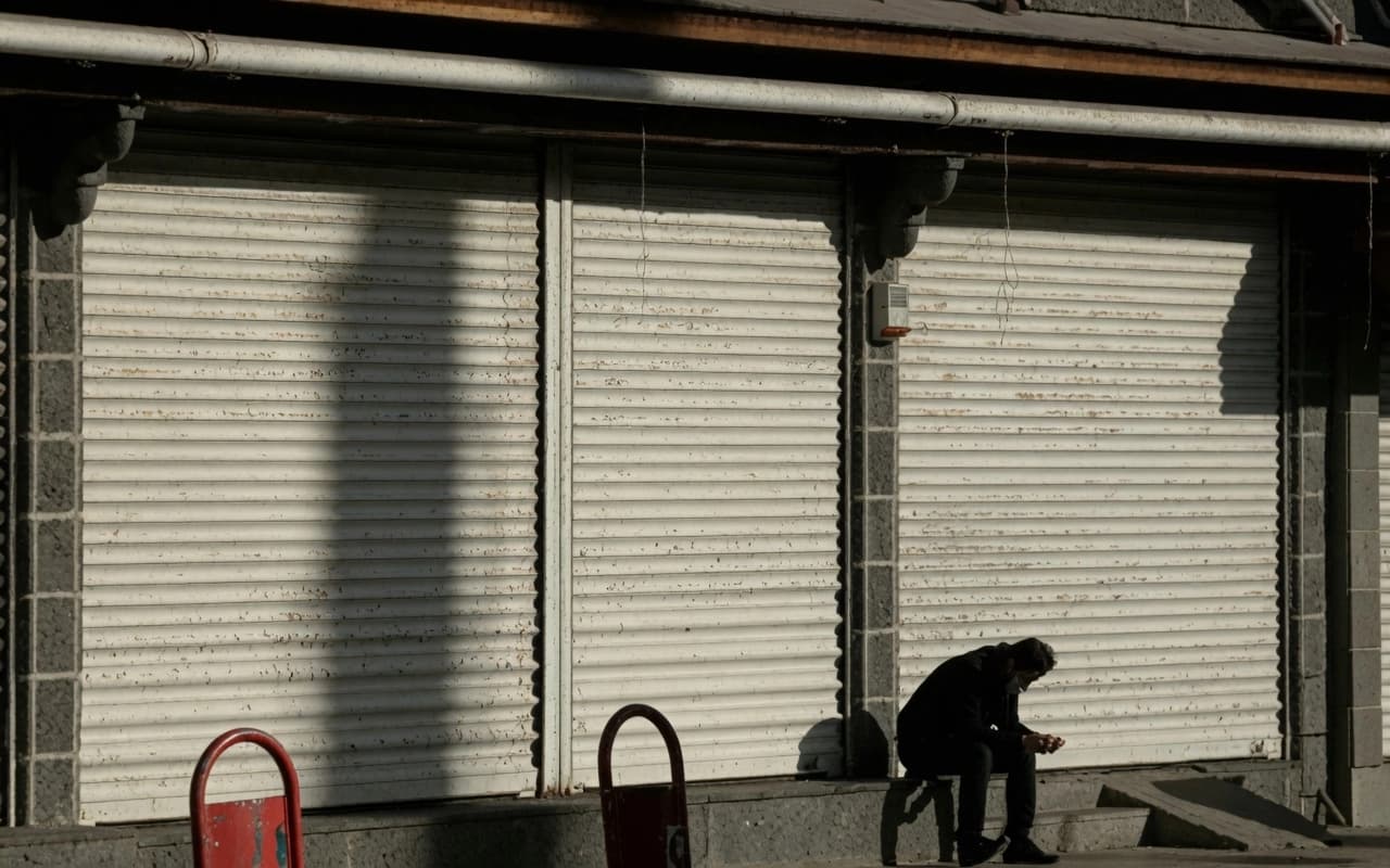 Kesek li ber dikaneke girtî rûniştiye / Wêne: Arşîv