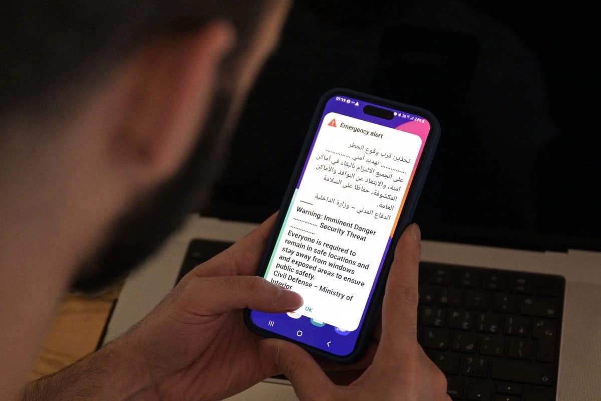 پیاوێکی کوێتی مۆبایلەکەی بەدەستەوەیە کە نامەیەکی ئاگادارکردنەوەی لەسەرە، لە کاتی لێدانی زەنگی ئاگادارکردنەوە بەهۆی هێرشێکی مووشەکی یان درۆنیی ئێرانەوە لە شاری کوێت؛ بەرەبەیانی 2ی ئەیلوولی 2026. (وێنە: AFP)