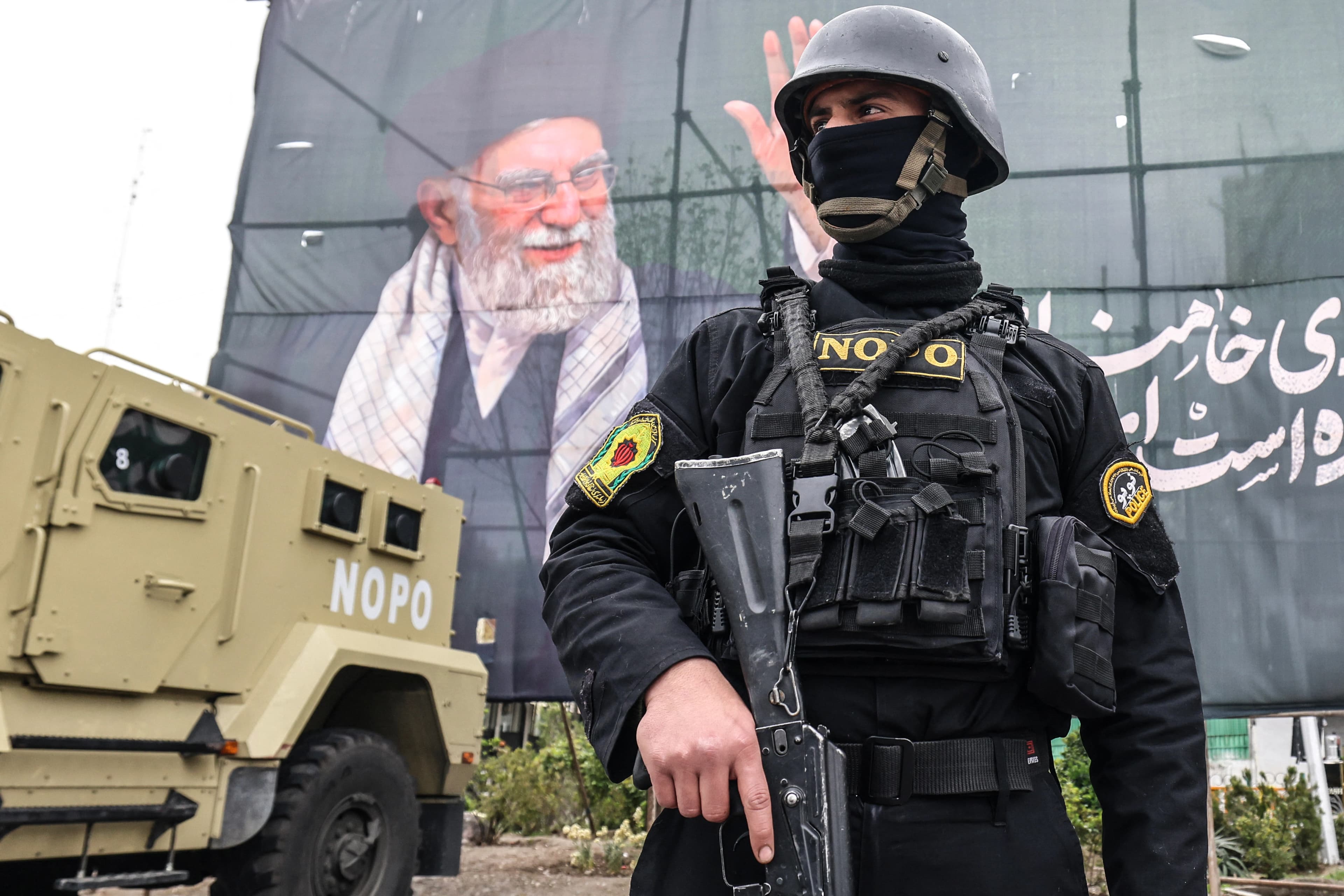 A member of the Iranian security forces stands near a banner featuring late Iranian Supreme Leader Ali Khamenei in Tehran. Photo: file/AFP