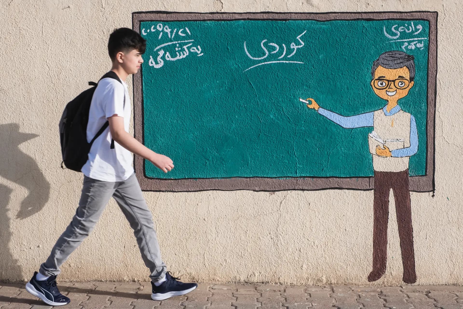 طالب يمر بجانب لوحة تتناول عن الدراسة الكوردية/ بلند طاهر - رووداو